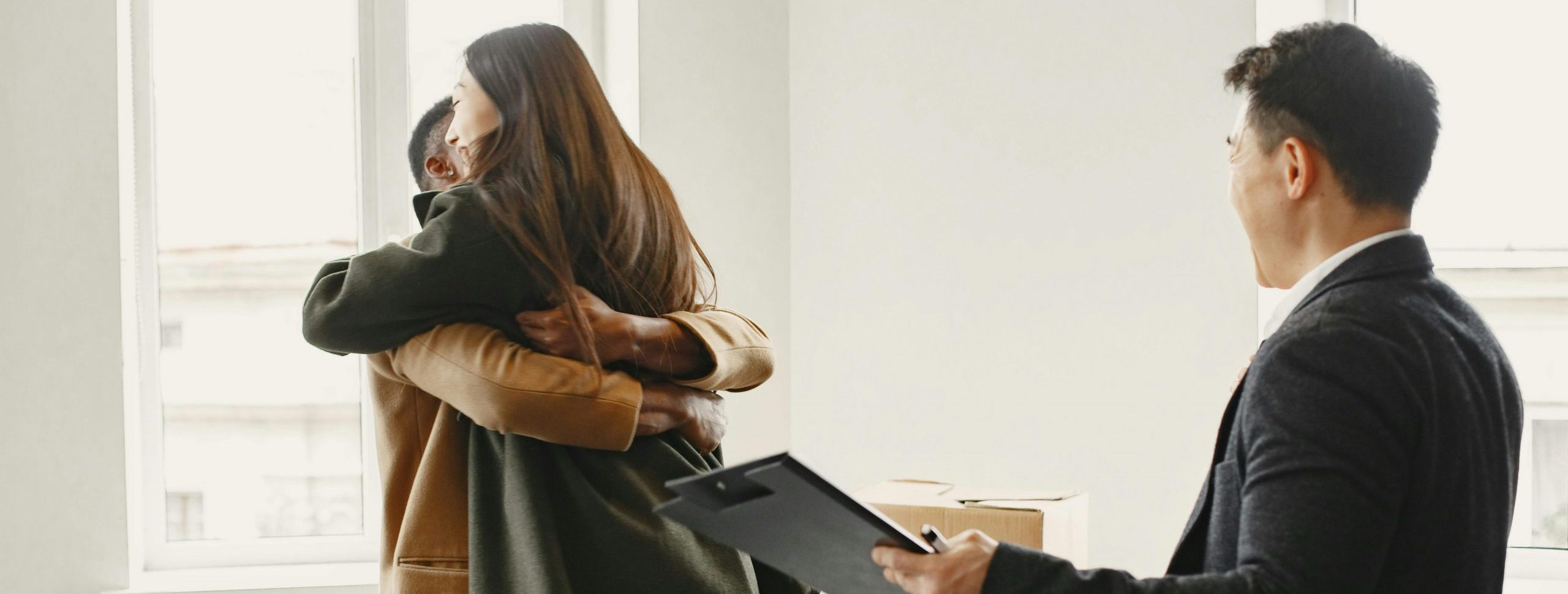 First-time homebuyers experience high levels of excitement and hug after purchasing their home, with their realtor standing by their side.