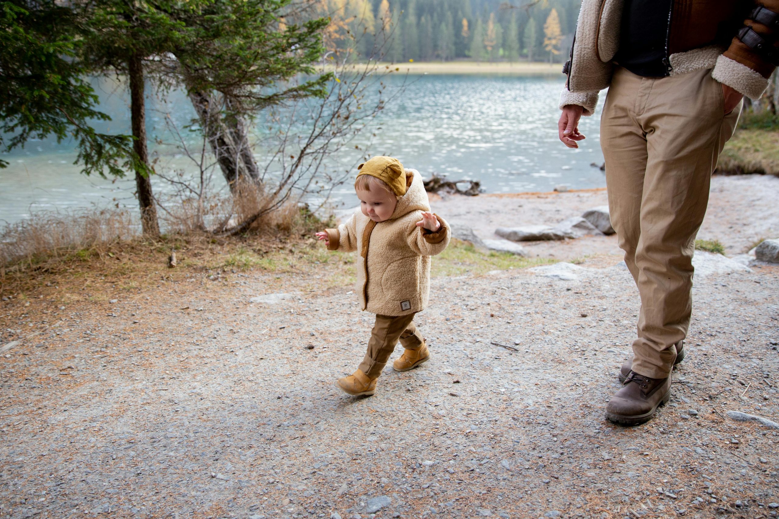 A small child and parent walking along a river trail in the fall.