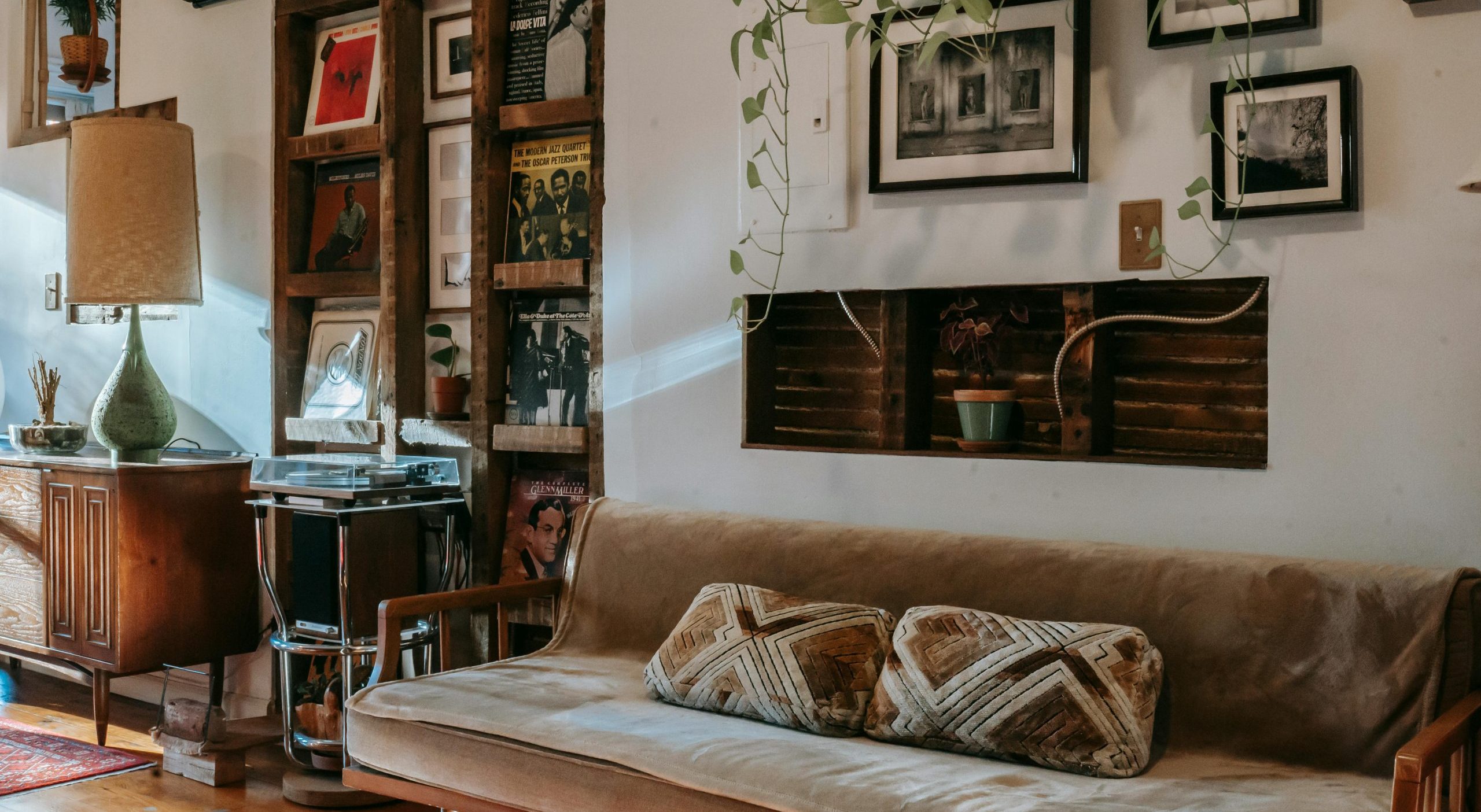 Cozy inside of a home in the fall, shelf with vinyl records collection between comfortable sofa and wooden cabinet in vintage styled room.